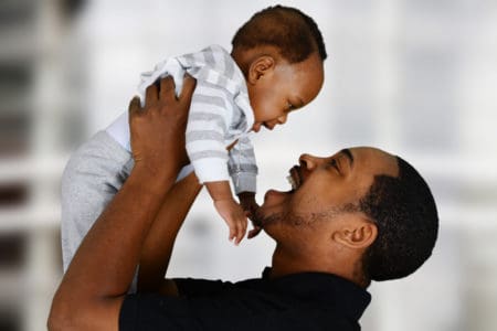 Sweet African dad holding up his beautiful baby boy