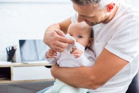 Father cleaning baby's nose