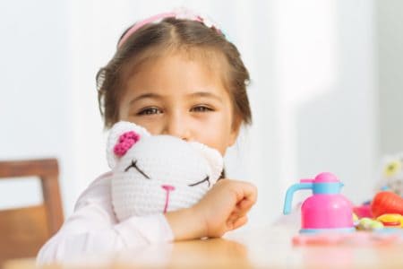 Little girl smiling with her knitted cat toy