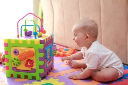 Smiling baby playing with colorful cube toy