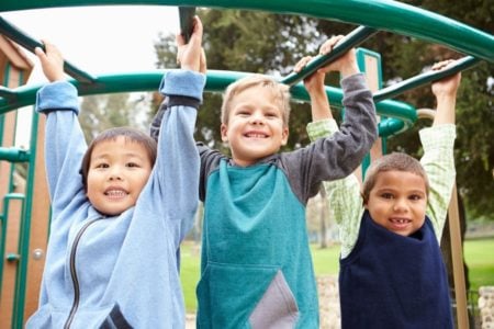 Three little boys climbing a monkey bar