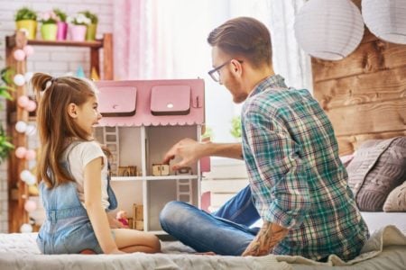 Little girl and dad playing with dollhouse