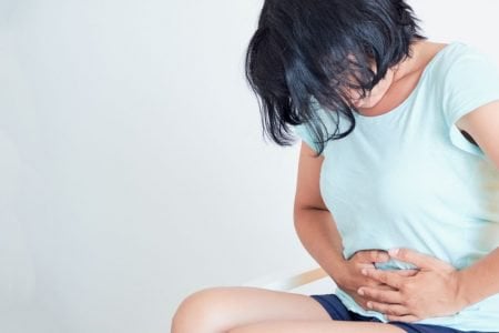 Woman holding her tummy while bowing her head in pain