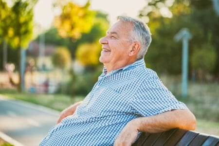 Smiling grandpa sitting on the bench at the prk