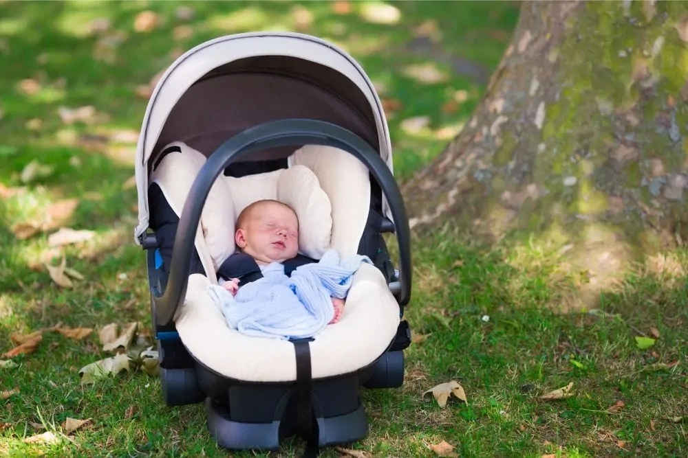 Baby sleeping inside a car seat on the grass