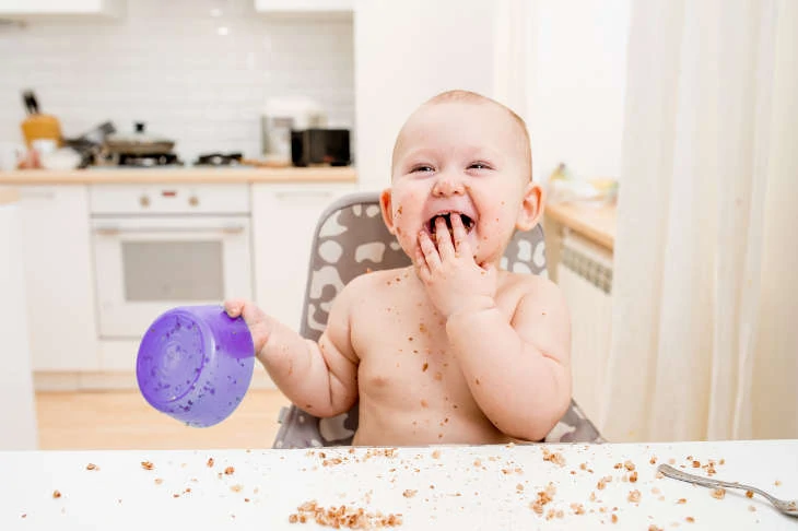 Messy baby eating at the table