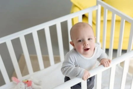 Baby standing inside a white crib