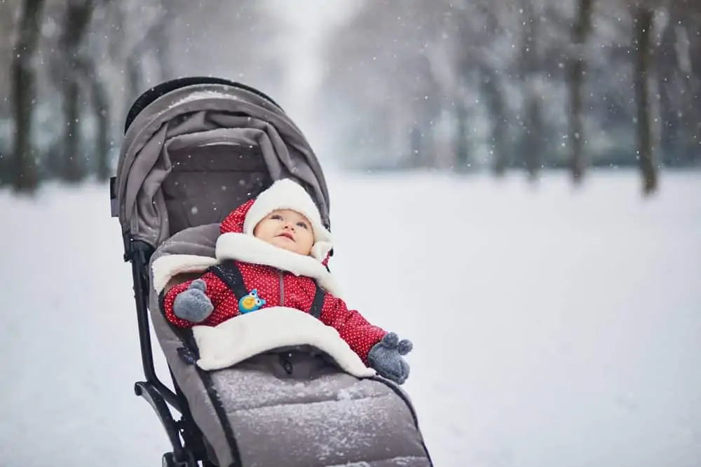 Baby girl out in the snow in stroller with footmuffs