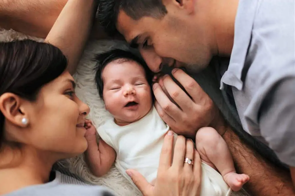 Portrait of happy parents cuddling their newborn baby