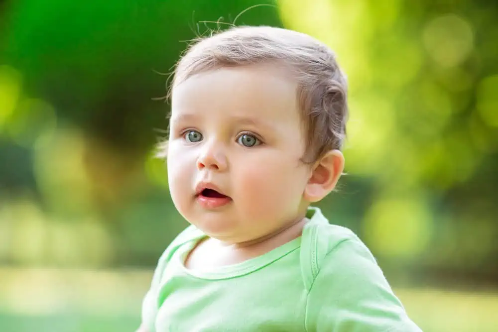 Cute baby sitting on the grass in the park