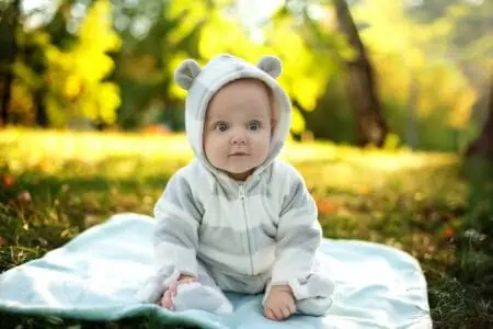 Baby in a funny costume sitting on the grass in the park