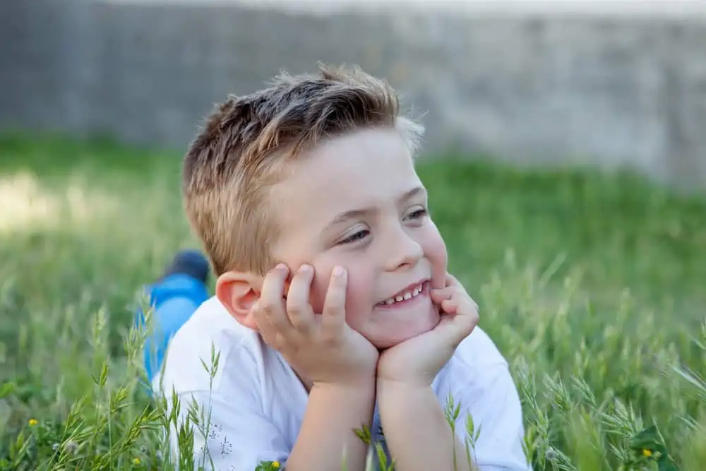 Happy little boy lying on the grass