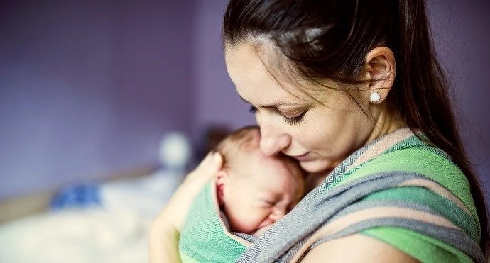 Mother holding her crying baby in a sling